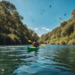 A kayak glides through a pristine river, surrounded by lush greenery and clear blue skies, with birds flying overhead and fish swimming beneath the surface